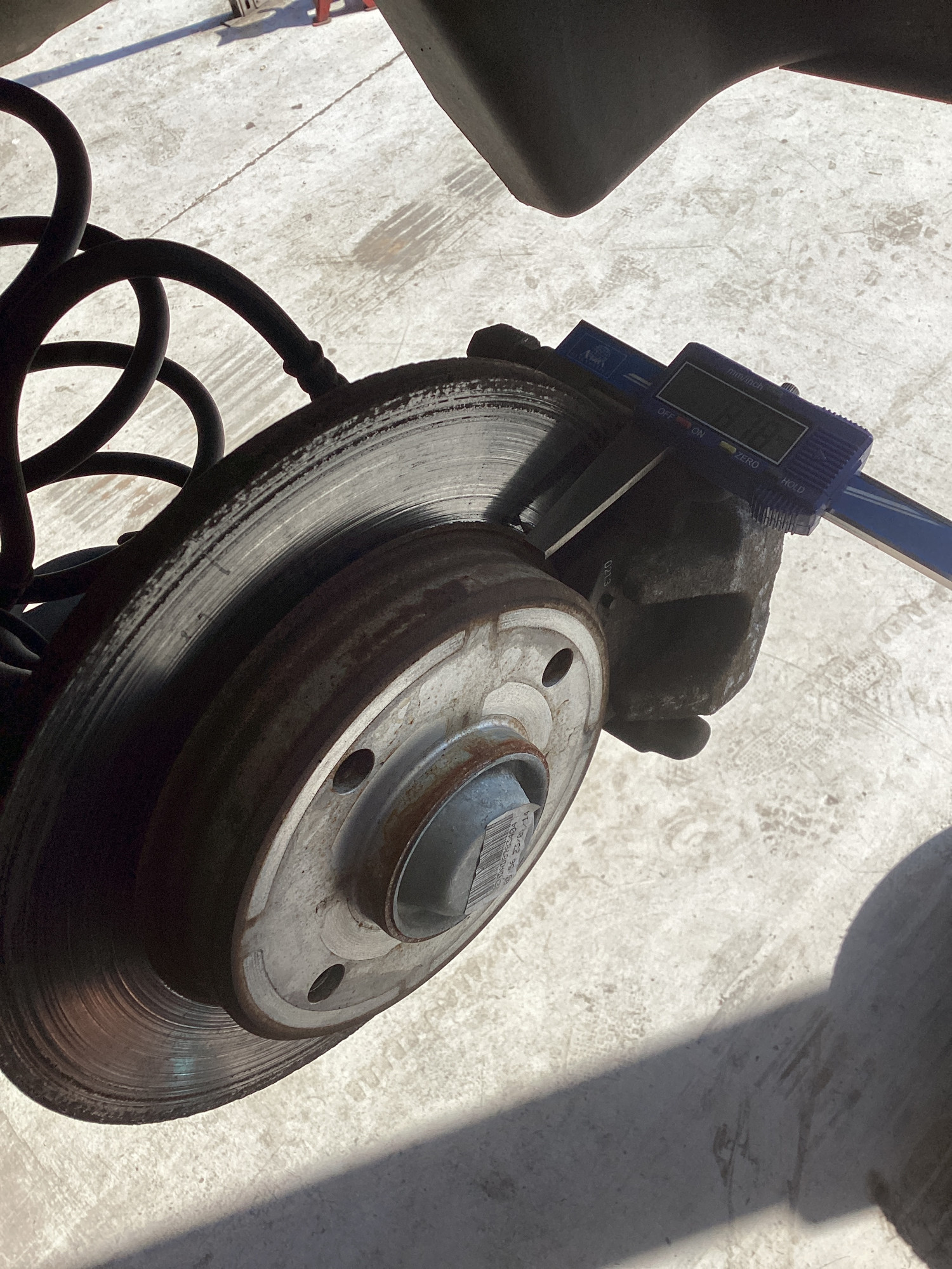 Digital vernier gauge measuring the thickness of a brake disc on a vehicle