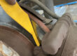 Yellow brake pad thickness gauge being used to measure remaining friction material on a rear brake pad