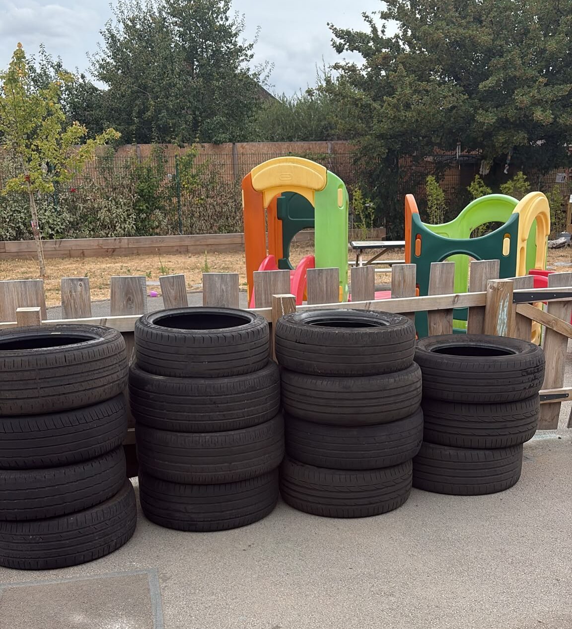 Stacks of scrap tyres ready for play beside the playground at a Nottinghamshire nursery