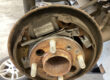 Rear drum brake with the drum removed showing rusty brake shoes, springs and handbrake lever mechanism