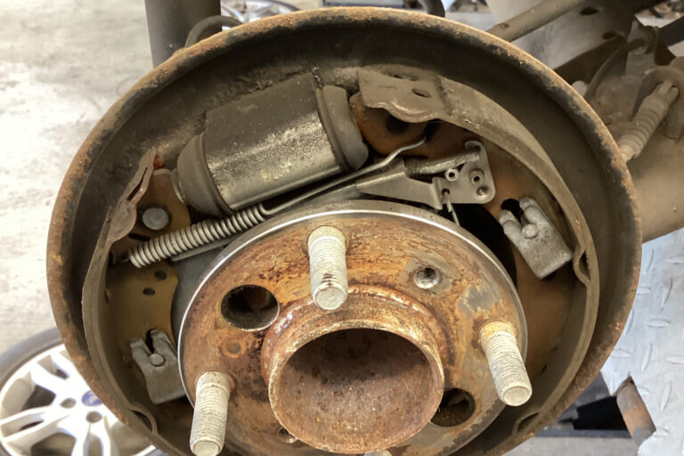 rear-drum-brake-handbrake-mechanism-corrosion-mot-failure.jpg Rear drum brake with the drum removed showing rusty brake shoes, springs and handbrake lever mechanism