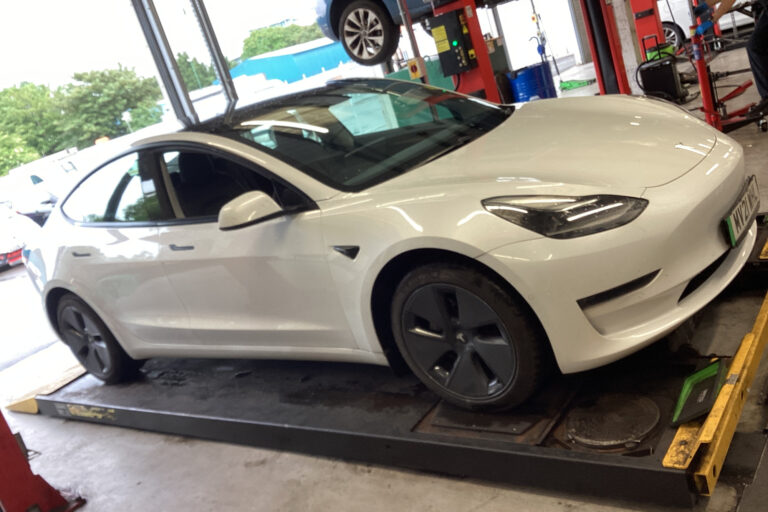 tesla-model-3-workshop-lindleys-autocentres-nottinghamshire.jpg White Tesla Model 3 on the ramp inside the Lindleys Autocentres workshop in Nottinghamshire