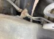 Corroded brake pipe union at the flexible hose bracket on a car's rear suspension