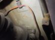 Heavily corroded rear brake pipe held in its retaining clip on the underside of a car