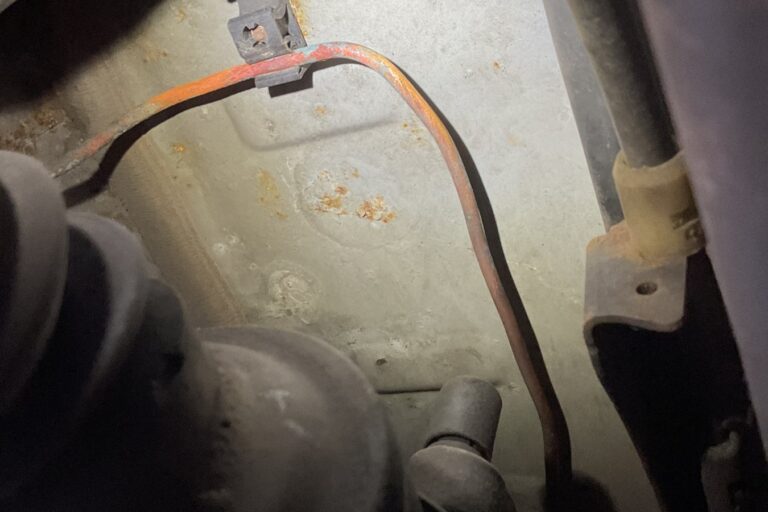 corroded-rear-brake-pipe-mot-advisory Heavily corroded rear brake pipe held in its retaining clip on the underside of a car