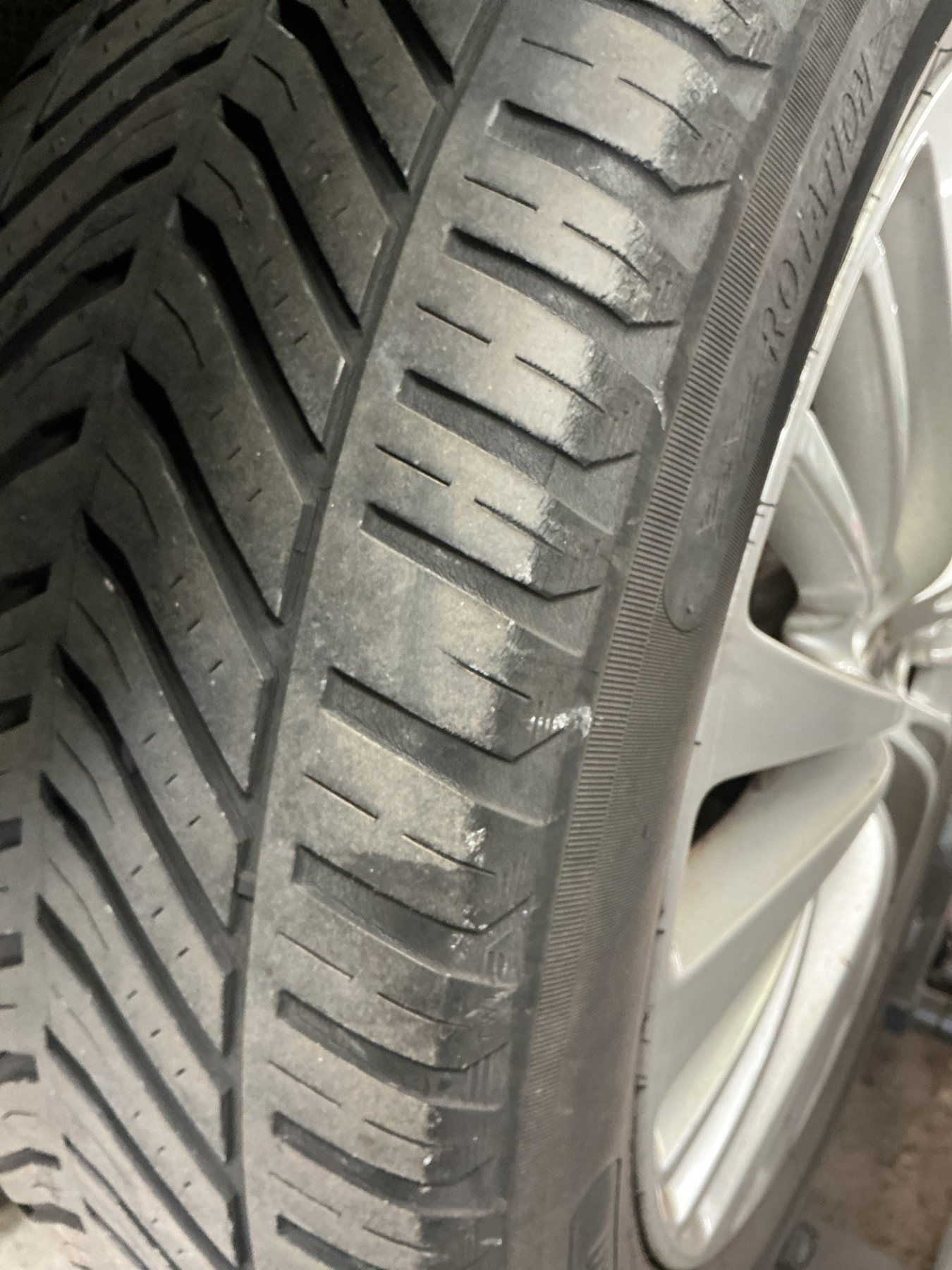 Fine cracks opening along the shoulder blocks of an ageing tyre on its alloy wheel
