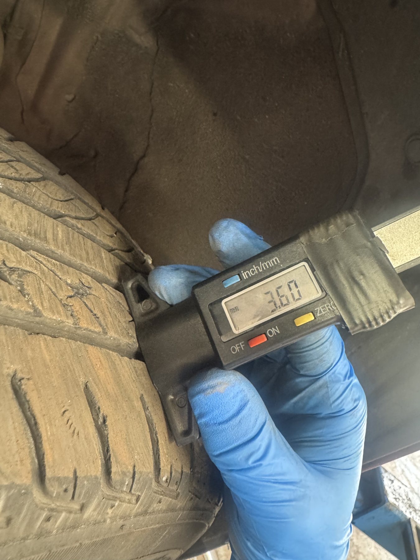Technician measuring the tread on a feathered front tyre with a digital depth gauge