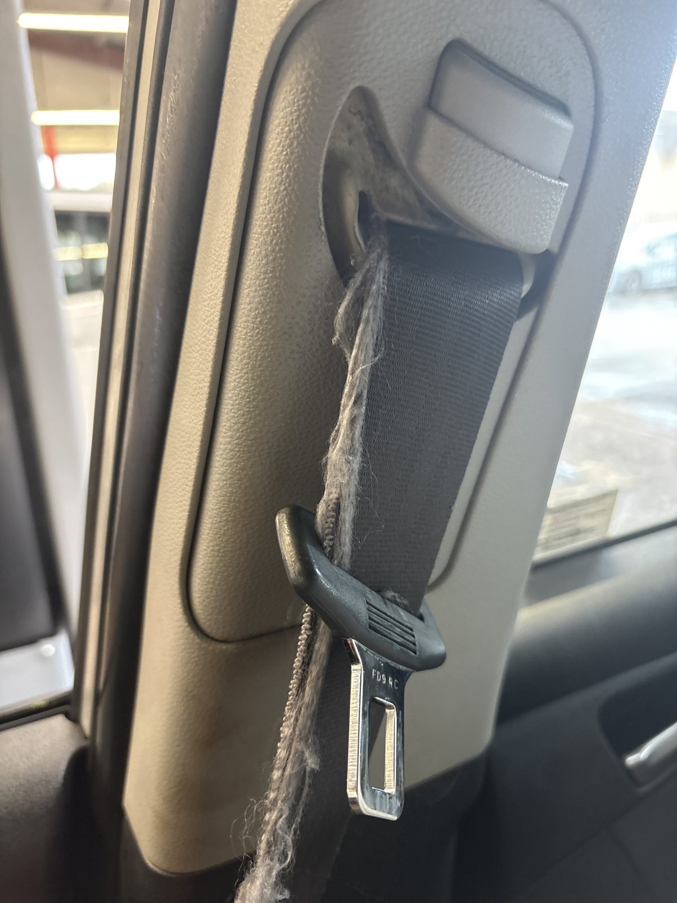 Frayed seat belt webbing running through the pillar guide